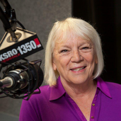 Smiling woman with white hair at a radio station microphone labeled KSRO 1350 AM, discussing How to Stay Balanced While in Service with Pat Kerrigan.