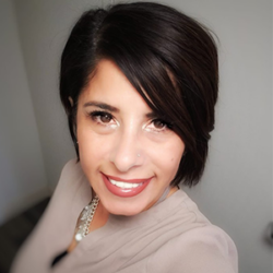 Smiling woman with short dark hair, wearing a beige top and necklace, in a well-lit indoor setting, inspired by How to Serve Vulnerable Communities with Alma Bowen.
