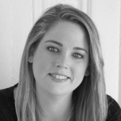 Woman with long straight hair smiling, wearing a dark top, in front of a white background. Black and white photo. Featured in "How to Provide Legal Aid to Disaster Survivors with Kendall Jarvis Esq.
