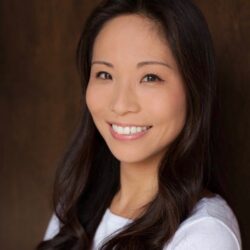 Smiling woman with long dark hair, wearing a white top, posed in front of a dark background—Chisato Fukuda Calvert exudes confidence and warmth.