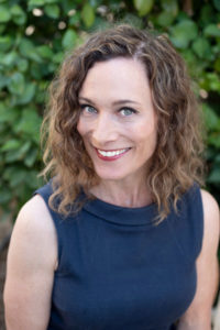 smiling woman in a blue dress and brown curly hair