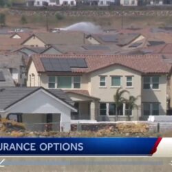 A suburban neighborhood with homes, some with solar panels; news banner reads Fire Insurance Options.