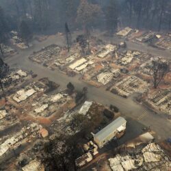 Aerial view of a neighborhood with homes destroyed by wildfire, leaving only foundations and charred debris.