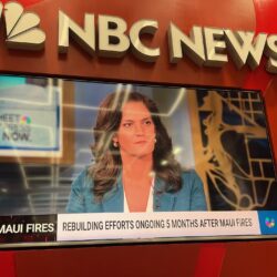 A woman speaks about Maui fire recovery on NBC News, displayed on a television with a red background.