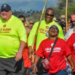 Group of people in bright shirts, smiling and walking together at an outdoor event.