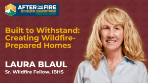 Laura Blaul smiles in front of a summit banner about creating wildfire-prepared homes for a leadership event.