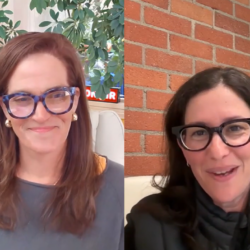 Two women with glasses smiling during a video call, one with a leafy background, the other with a brick wall.