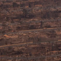 Aerial view of a neighborhood devastated by fire, with destroyed homes and scorched earth.