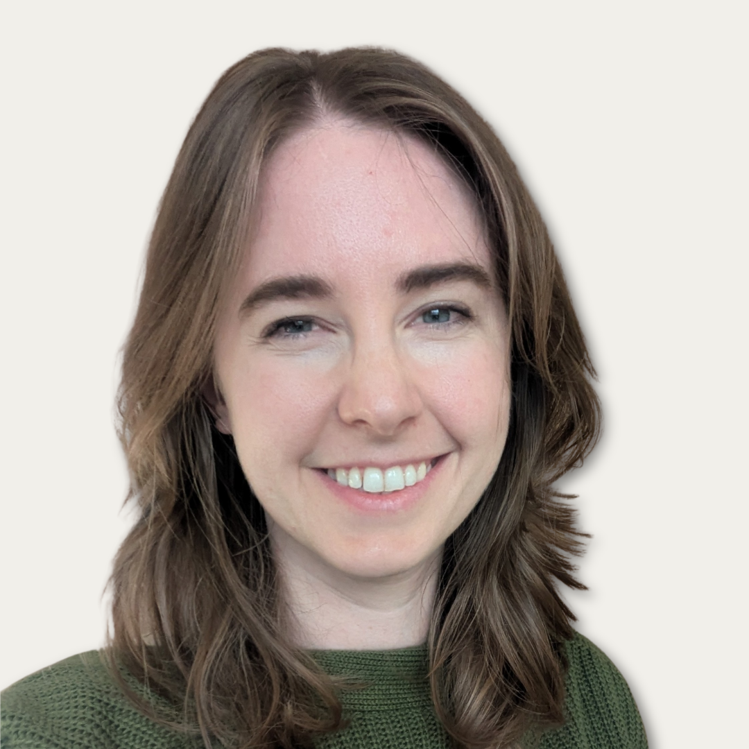 Woman with brown hair wearing a green sweater, smiling at the camera against a light background.