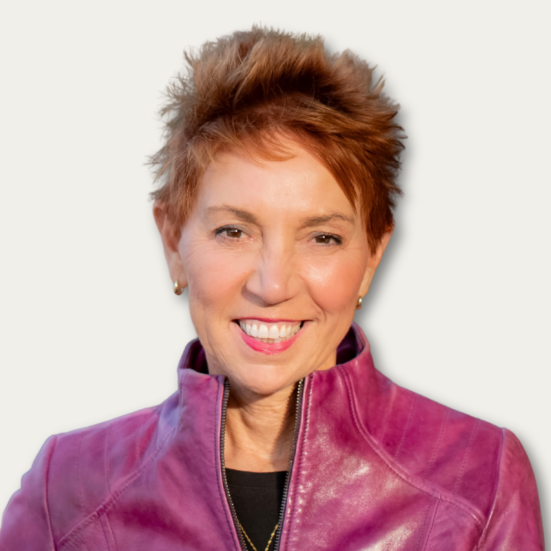 Smiling woman with short, spiky hair wearing a magenta leather jacket against a plain background.