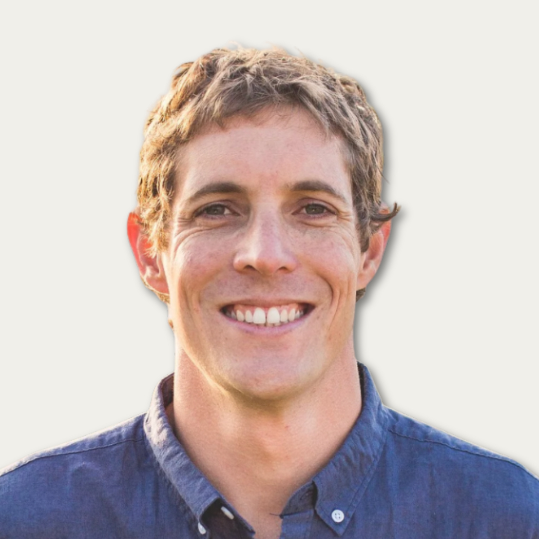 Smiling person with short, light brown hair wearing a blue shirt, pictured against a plain white background.