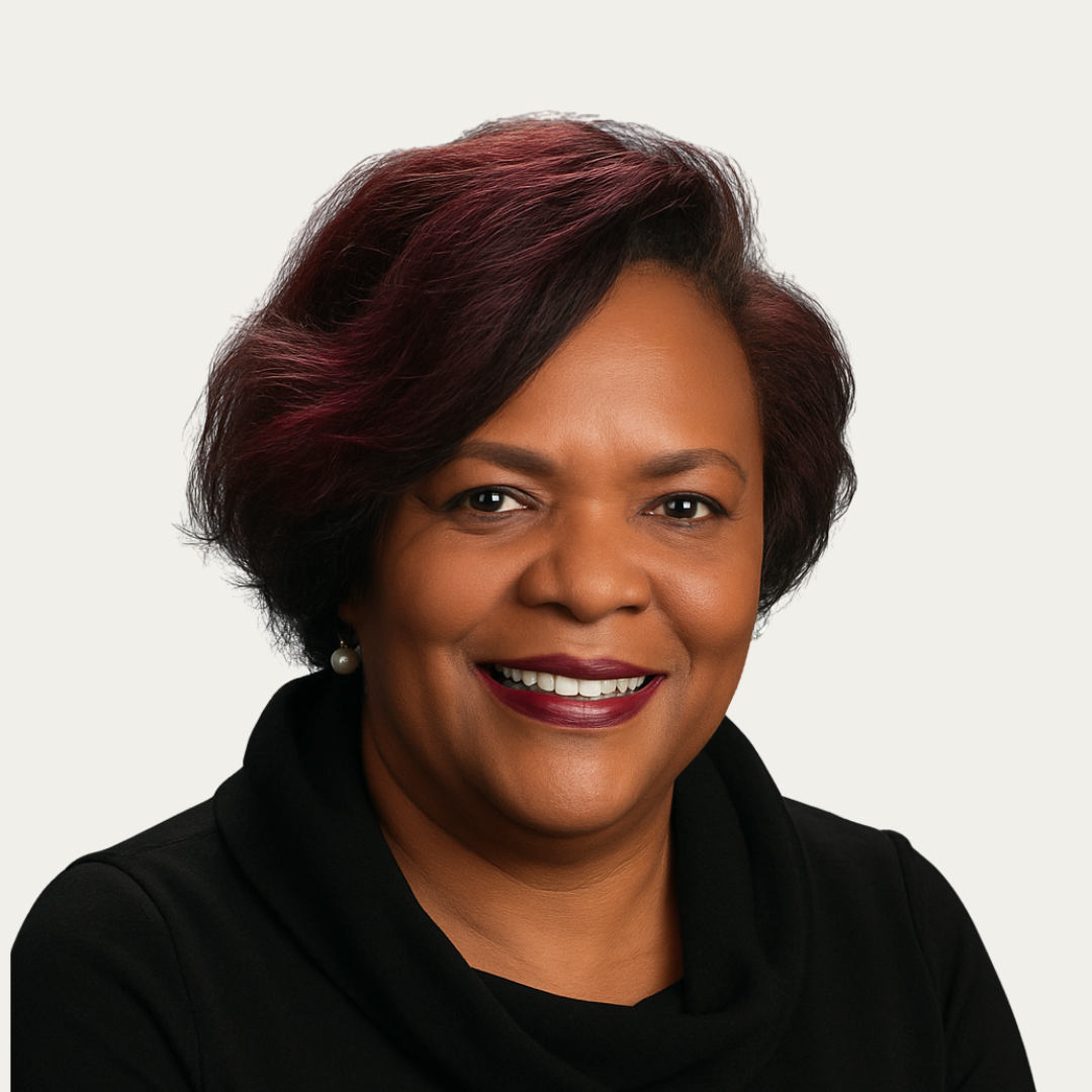 Smiling woman with short, dark hair wearing a black top and pearl earrings on a light background.